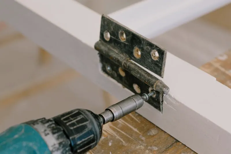 Nail positioned under a door hinge pin ready to be tapped out with a hammer